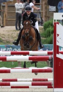 Emma Matu sur son cheval faisant du saut d'obstacle vue de face